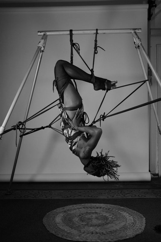 A woman hanging upside down on a pole